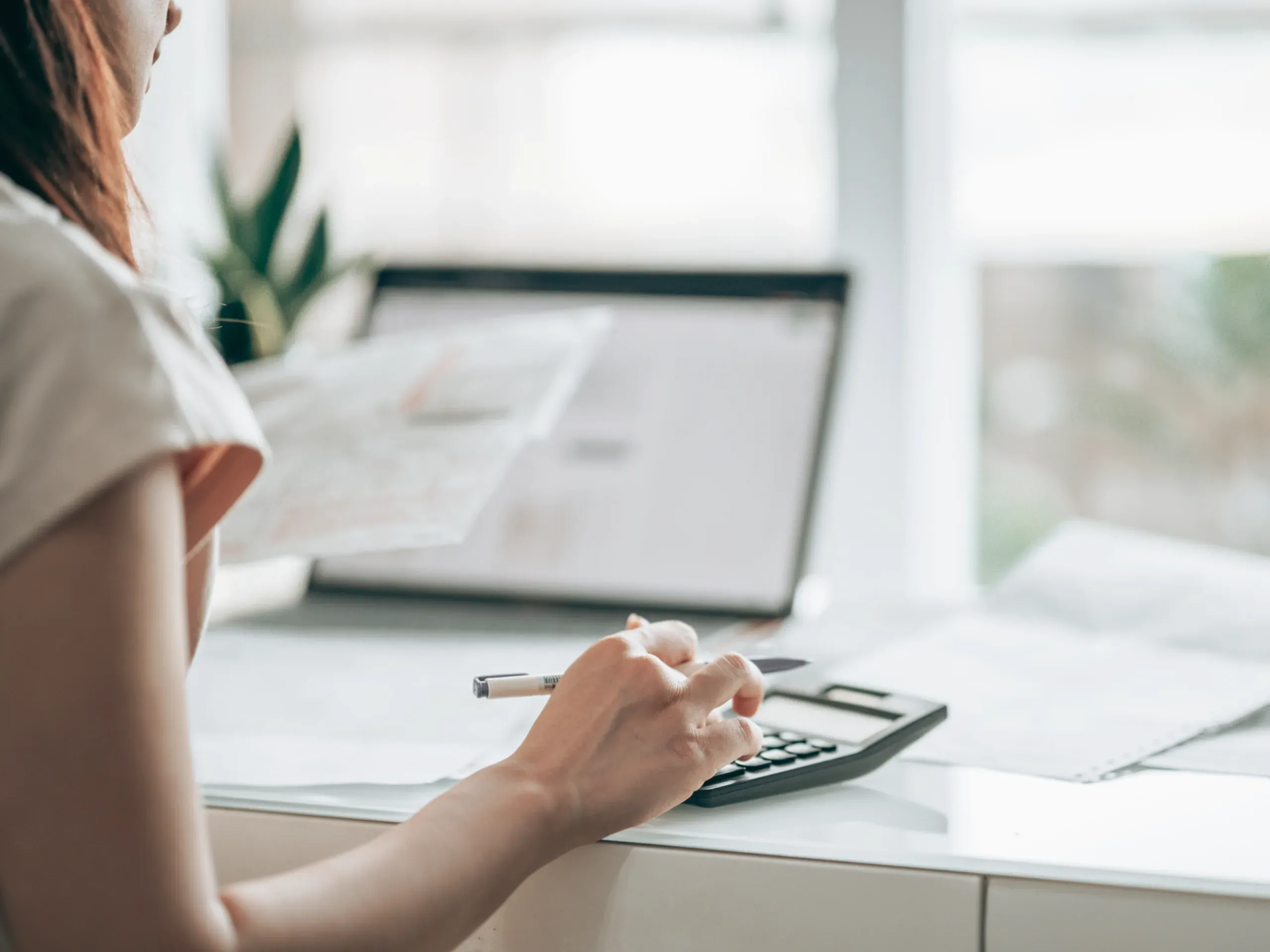 Woman in front of a laptop using a calculator